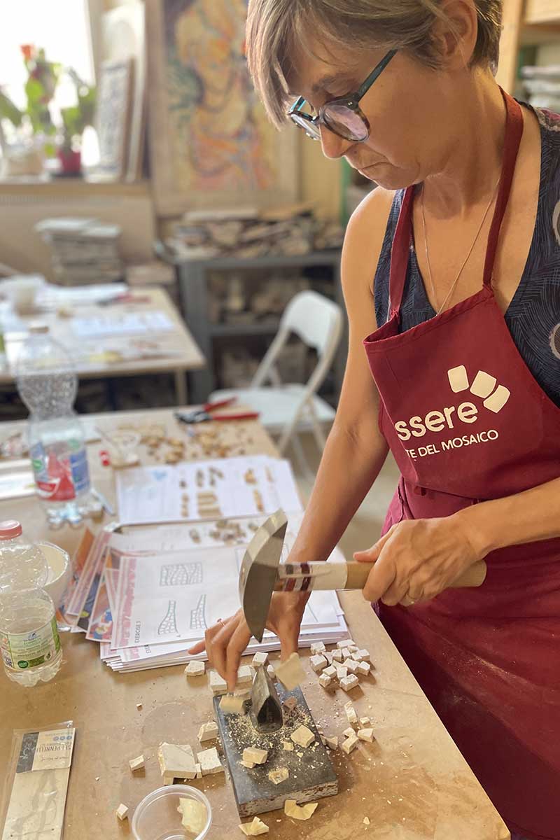 A student cutting some pieces of marble during the professional trainin in mosaics at the In Tessere School