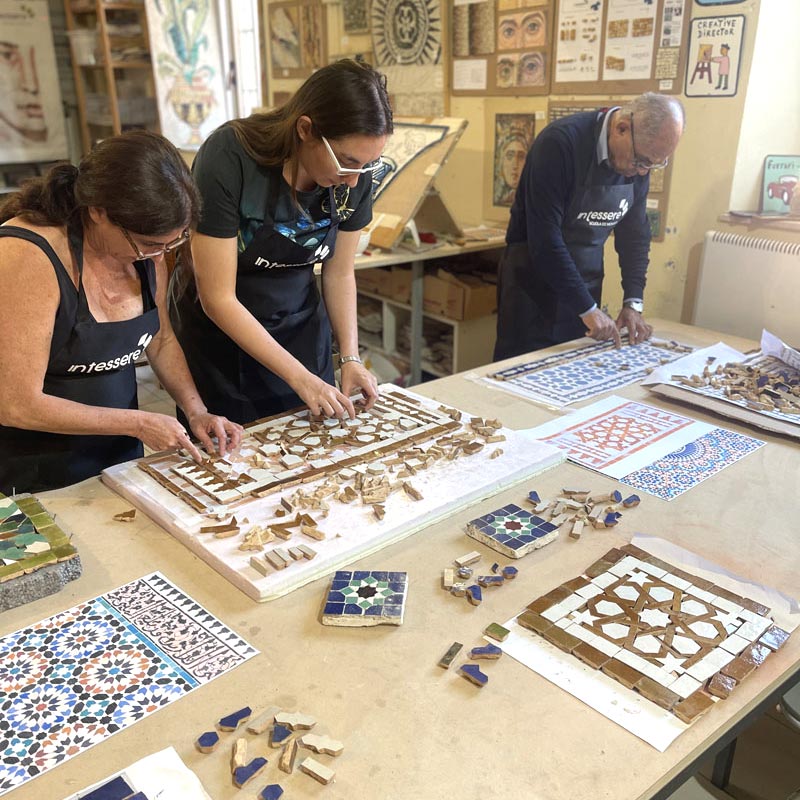 Group workshop of Moroccan Mosaic Zellige in Italy. Three people working on a Moroccan zellige mosaic