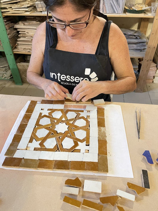 A woman is creating a colorful Moroccan Ceramic mosaic in a Mosaic School
