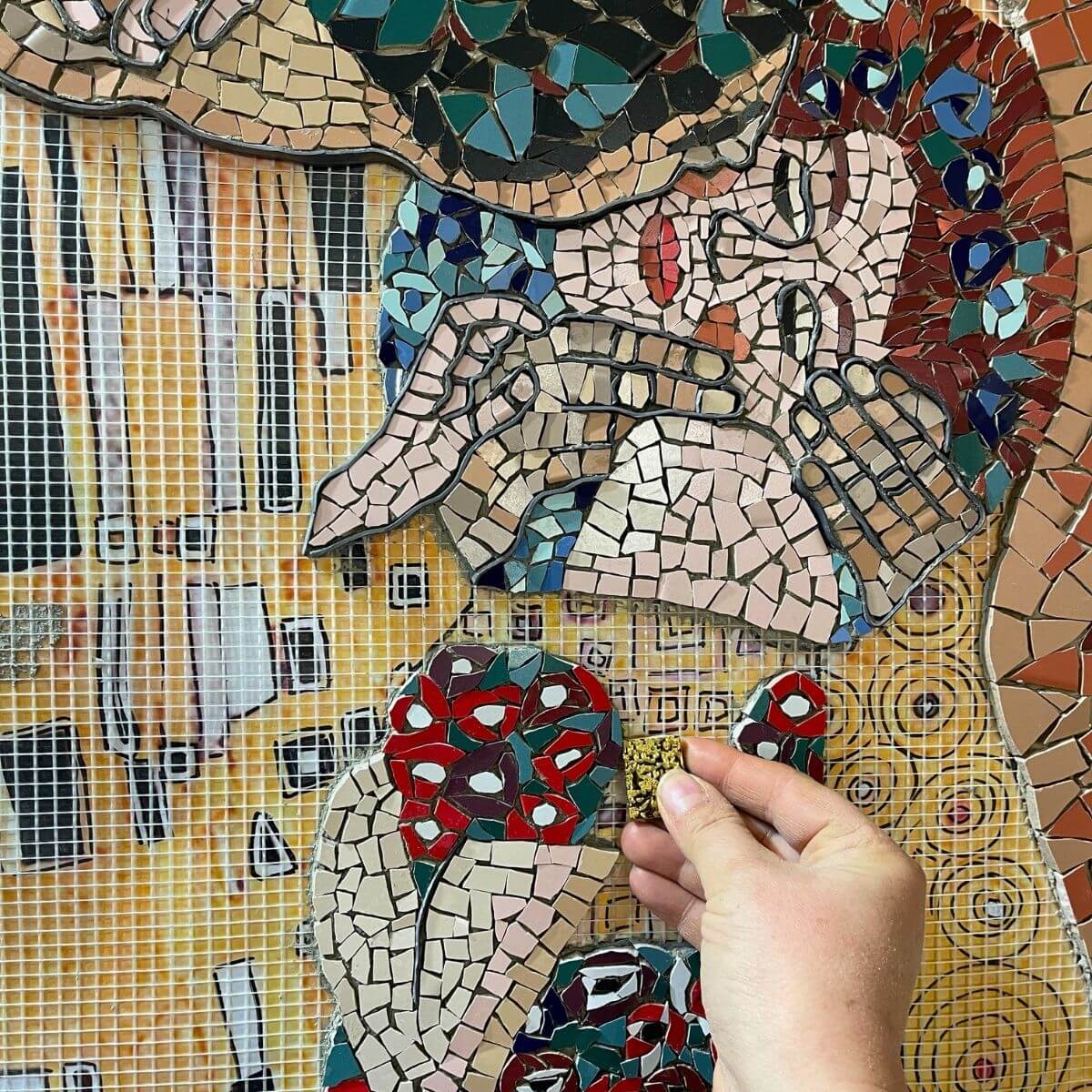 Studenti al lavoro su una grande composizione policroma in ceramica Trencadís. Mosaico che rappresenta il bacio di Klimt