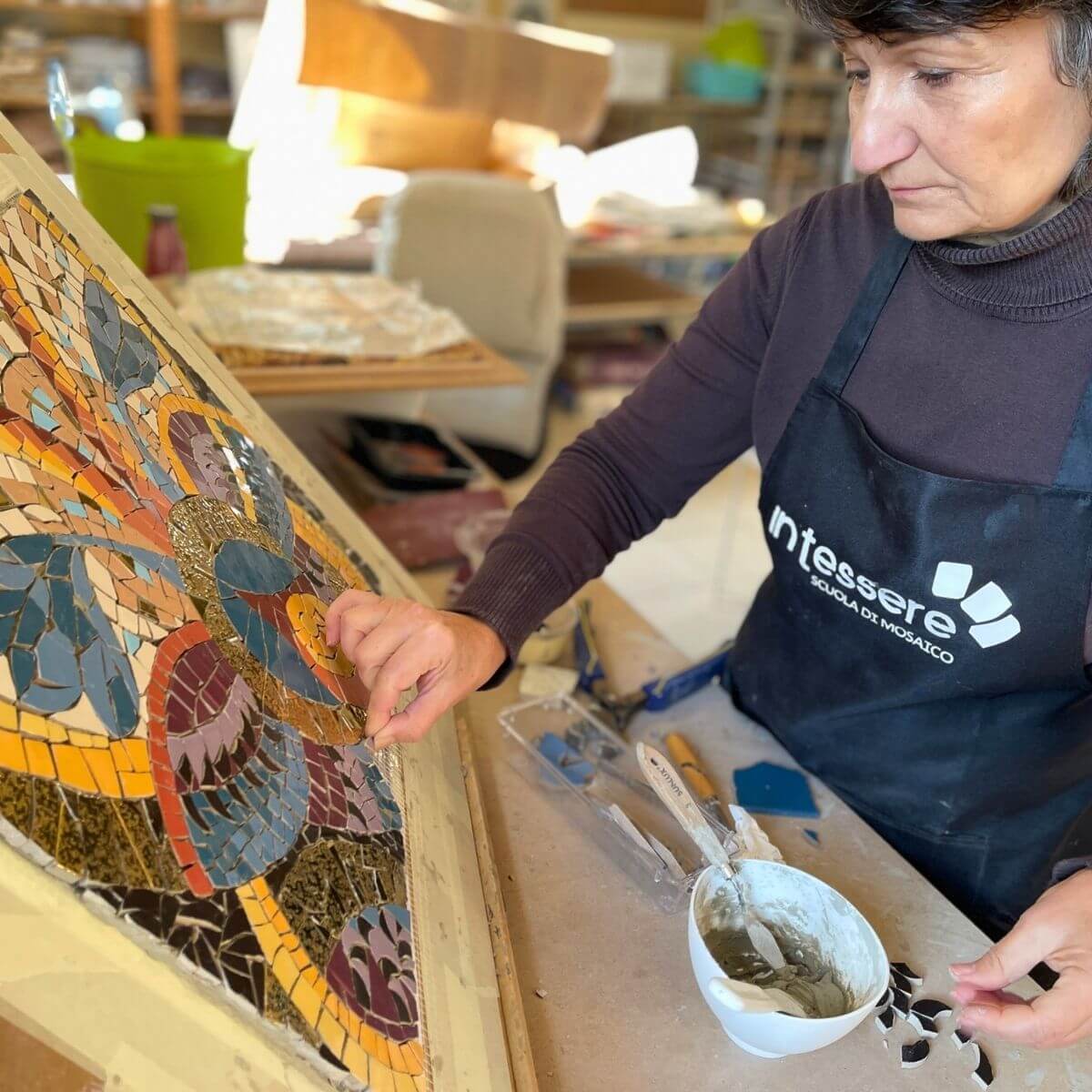 Partecipanti realizzano un mosaico con tessere in ceramica di recupero nel corso Trencadís alla scuola In Tessere.