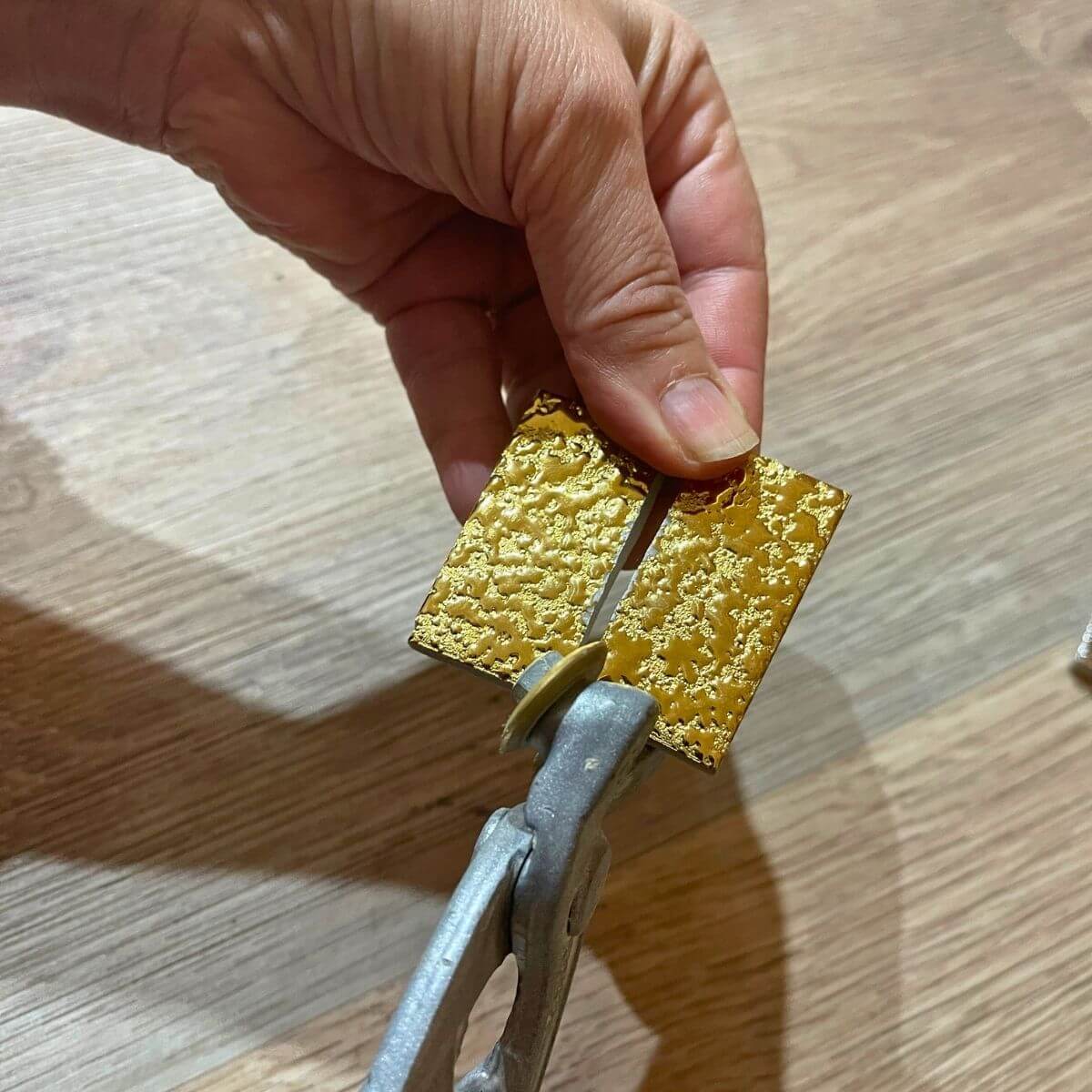 Taglio manuale di tessere in ceramica oro con texture 3D sulla superficie per mosaico con pinza da mosaicista