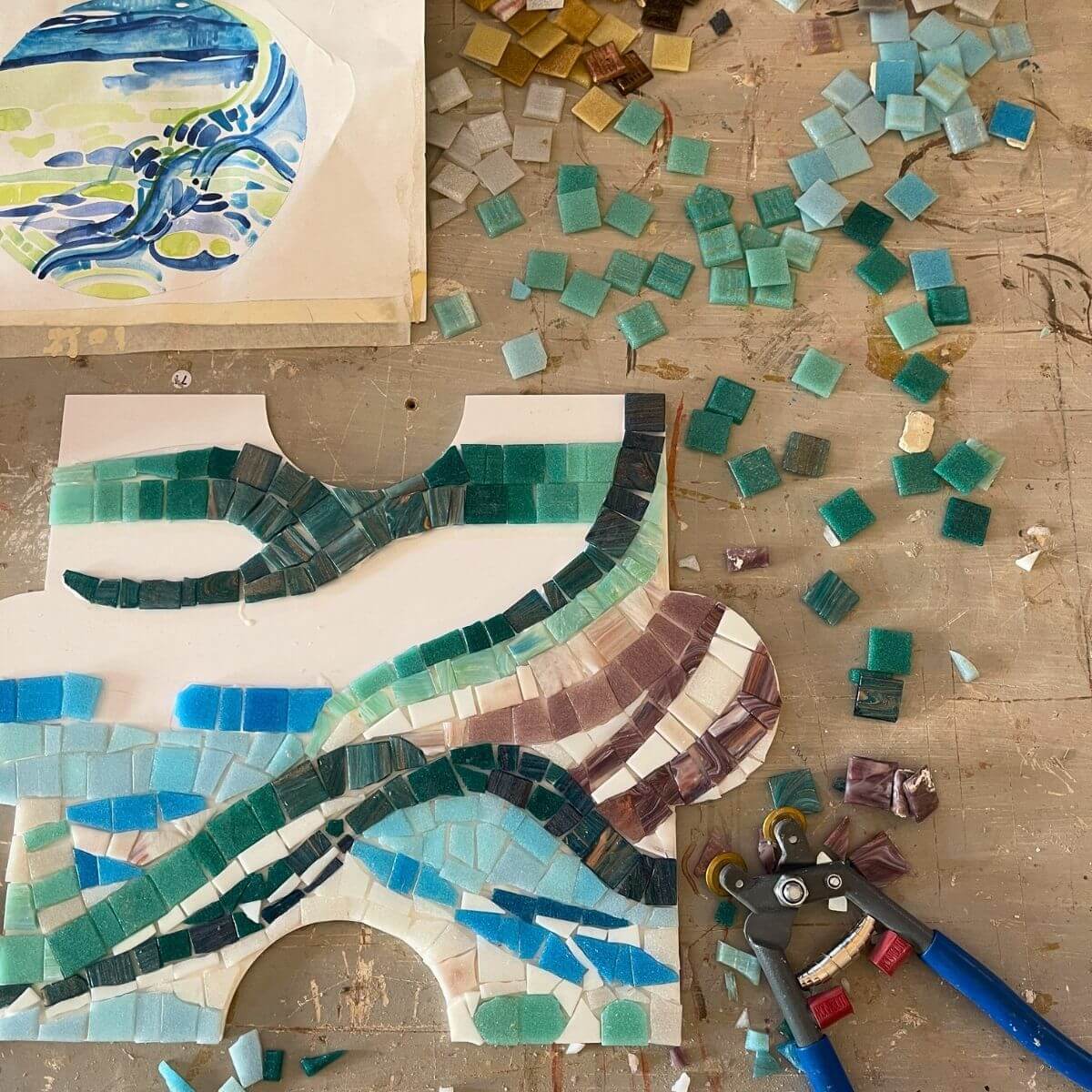 Dettaglio di mosaico industriale in lavorazione con tessere verdi e azzurre in vetro o smalto