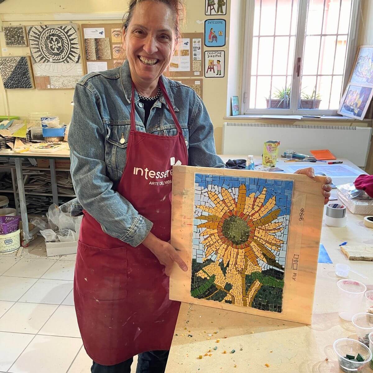 Allieva mostra felice la sua opera di mosaico moderno creata durante il corso della scuola di mosaico In Tessere