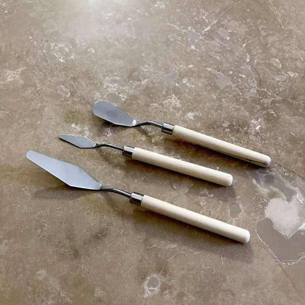 Three different metal spatulas with wooden handle for mosaics